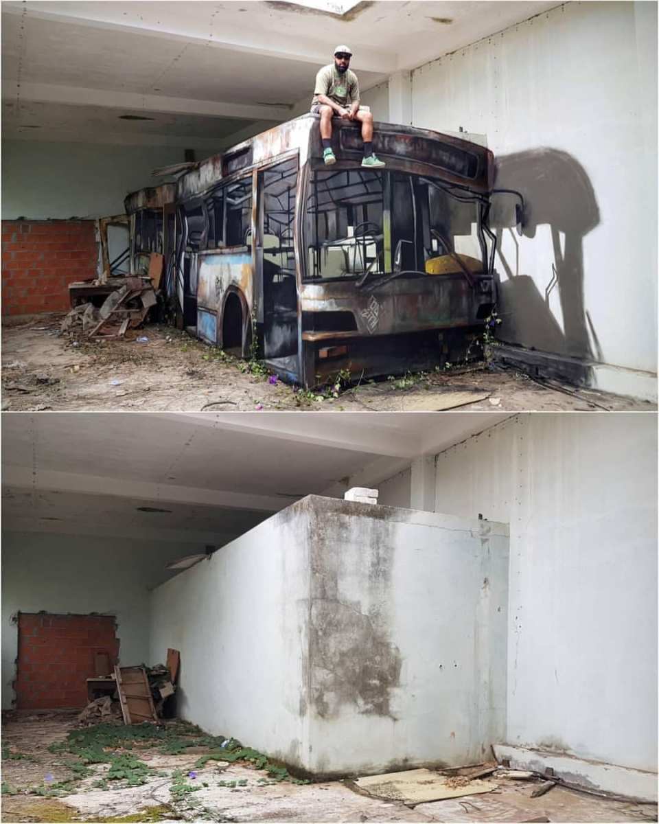 Street art illusion by Odeith depicting a lifelike, rusted bus in an abandoned indoor space. The artist skillfully uses shadows and perspective to make the bus appear three-dimensional and decaying, blending seamlessly with the surrounding neglected environment. Odeith himself is sitting on top of the painted bus, adding a sense of realism to the trompe-l'œil piece. The comparison with a photo of the empty, blank wall beforehand highlights the transformation and creativity behind the artwork.