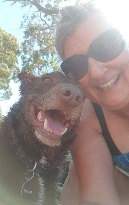 Selfie with grinning dog, wet from a swim. He's a red kelpie. His face and mine are close. I've got on sunglasses and I'm smiling.