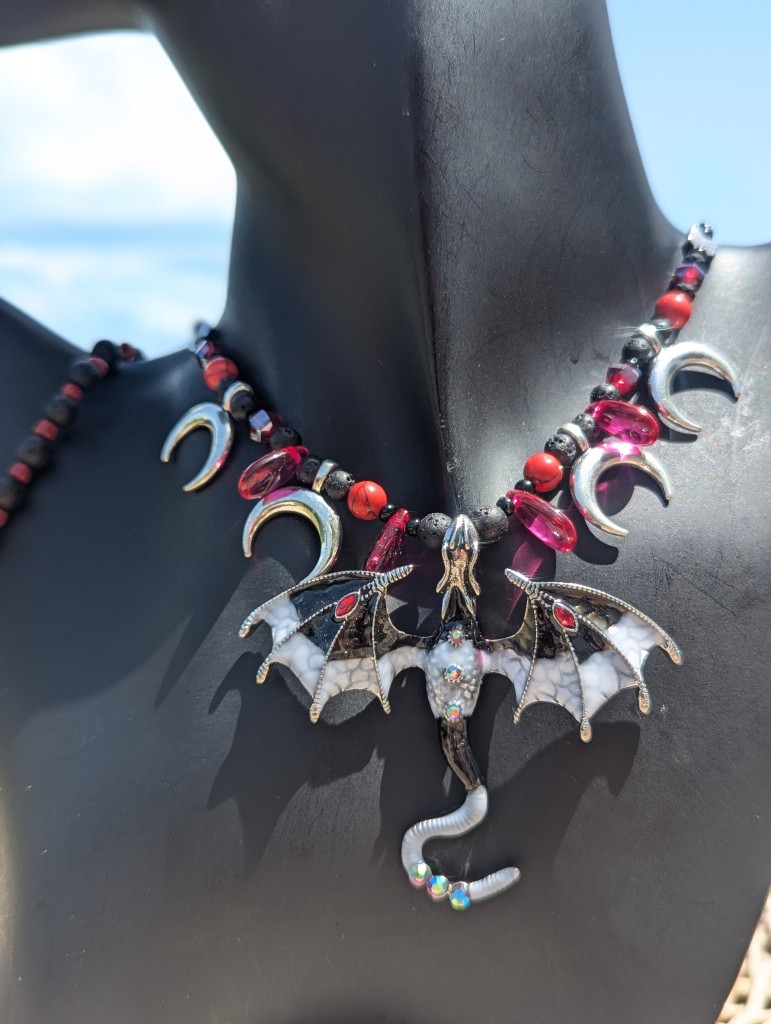 Welcome to the Fantasy World! And this is the Lava Dragon Set with black white dragon with red drops on its wings, crescent silver moons and red drop pendants, black red bracelet 

on a black doll, necklace close up