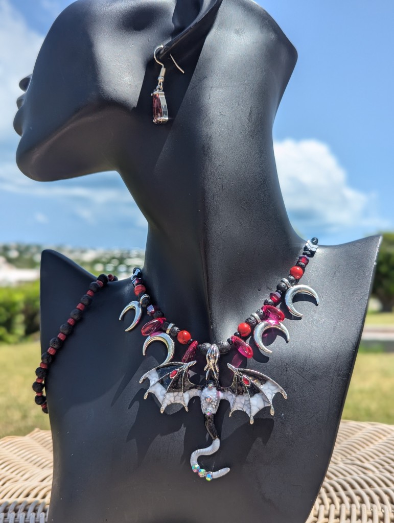 Welcome to the Fantasy World! And this is the Lava Dragon Set with black white dragon with red drops on its wings, crescent silver moons and red drop pendants, black red bracelet and red crystal drop earrings.

full set photo on a black doll, green garden and blue cloudy sky above