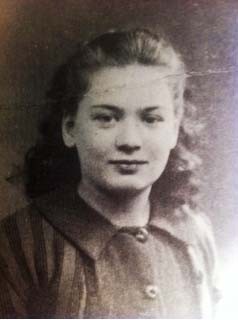 Black and white photograph of a young woman,  looking directly at the camera with a subtle smile, wearing a striped blouse with buttons.