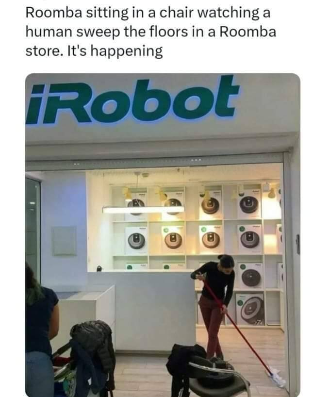 Roomba sitting in a chair watching a human sweep the floors in a Roomba store. It's happening.