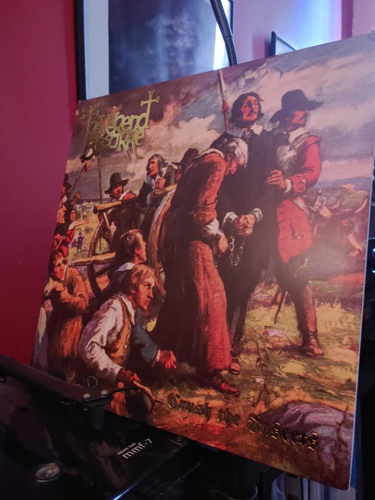 Reverend Bizarre's album Crush The Insects leaning beside a record player. Cover art depicts a scene from the English Civil War or a Witch Trial