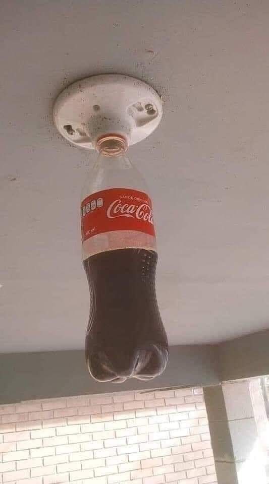 A half-full bottle of Coca-Cola screwed into a light socket.