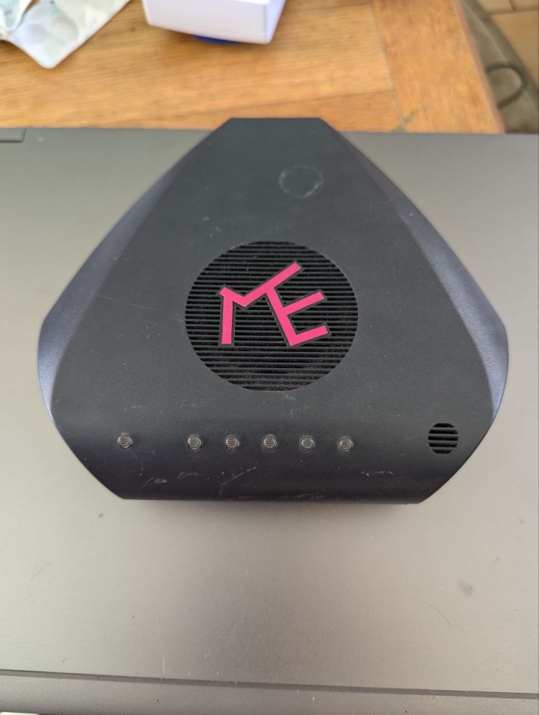 The top of a modem. It has a hot pink logo on the top, and 6 buttons on the front.