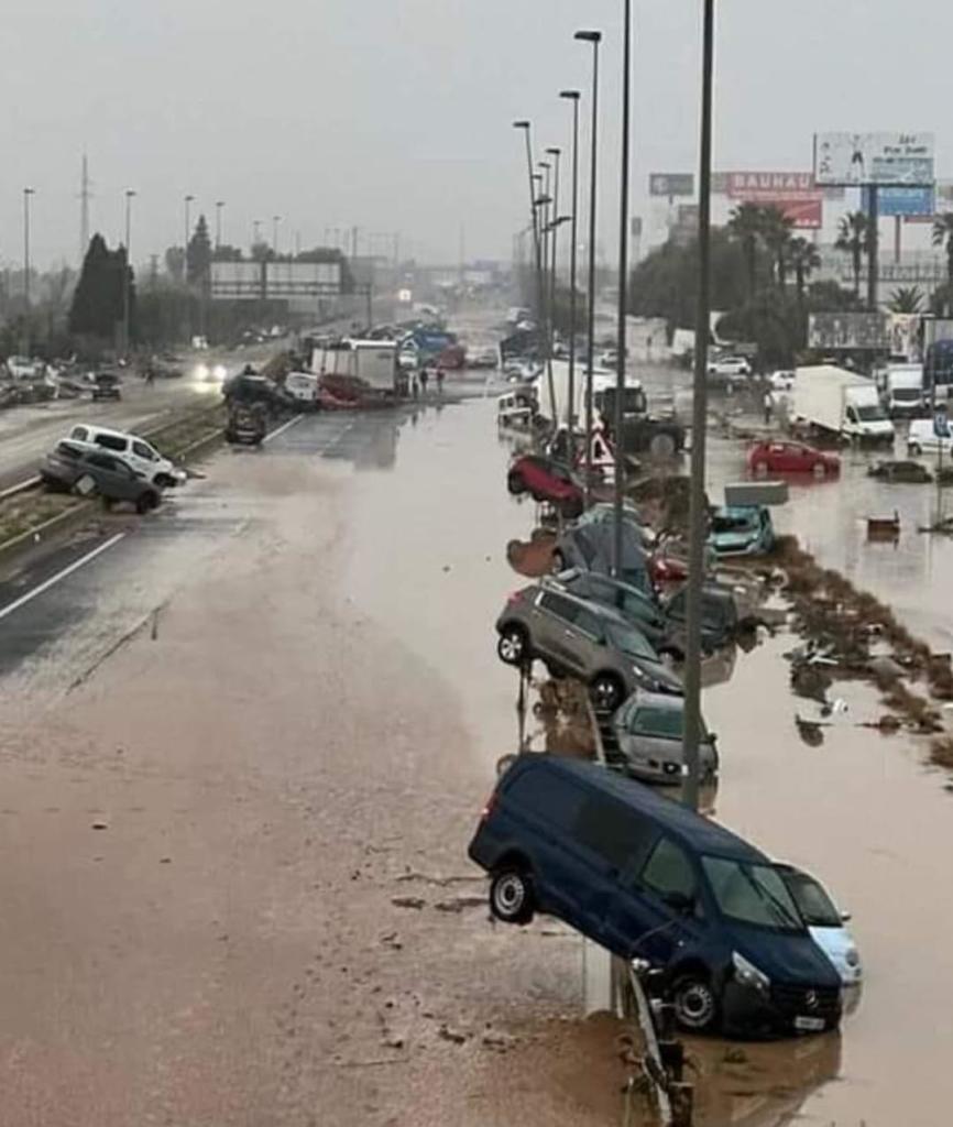 Imagen de una carretera de varios carriles inundada, repleta de coches abandonados y apilados los unos sobre los otros