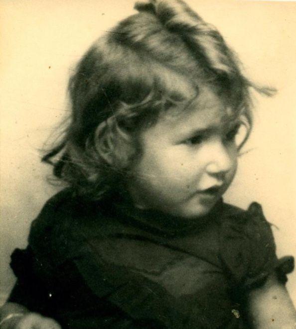 Vintage black-and-white photograph of a young girl with curly hair, looking to the side.