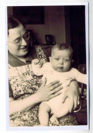 Vintage photograph of a woman holding a baby, both seated indoors.