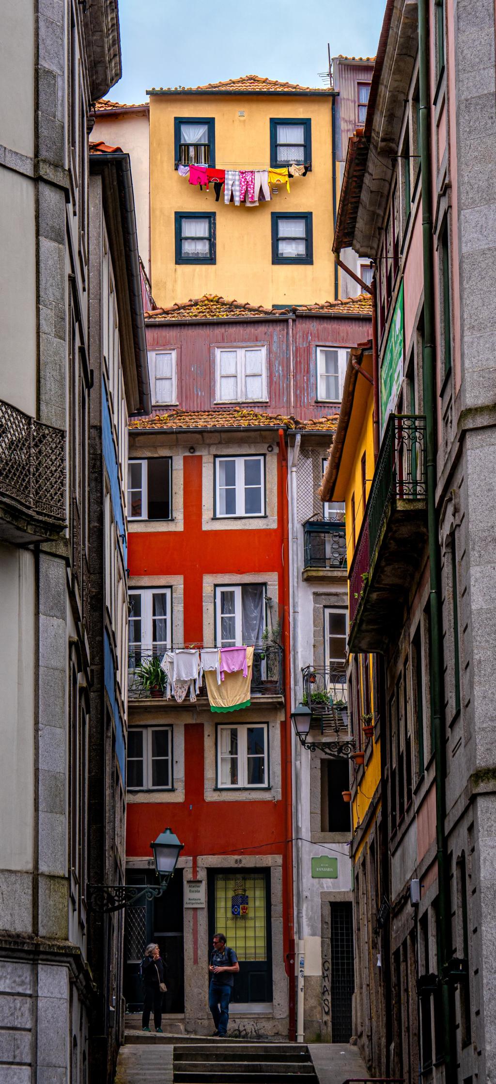 Color photo looking up a narrow street with laundry hanging from the buildings at the end. 