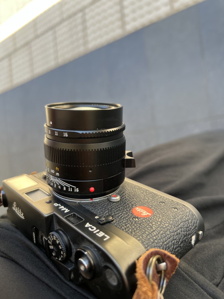 A Leica M4-P mechanical 35mm camera slung on a shoulder strap.