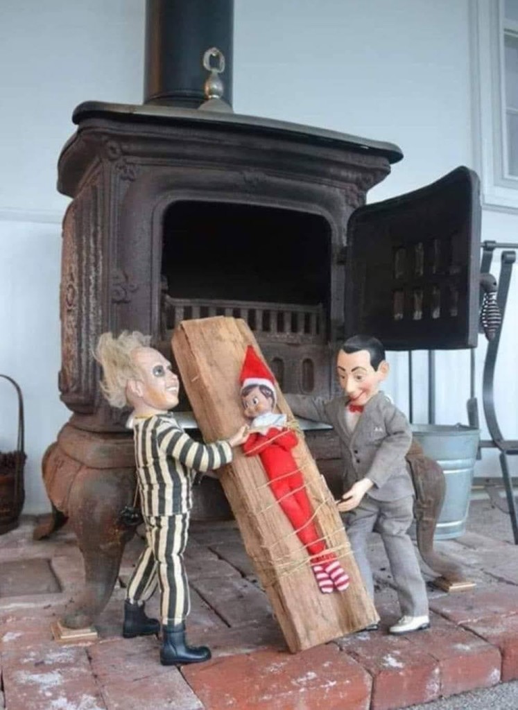 Beetlejuice and Pee-wee Herman loading Elf-on-the-Shelf, strapped to a piece of wood, into an antique stove.

Dolls be on the naughty list for sure.