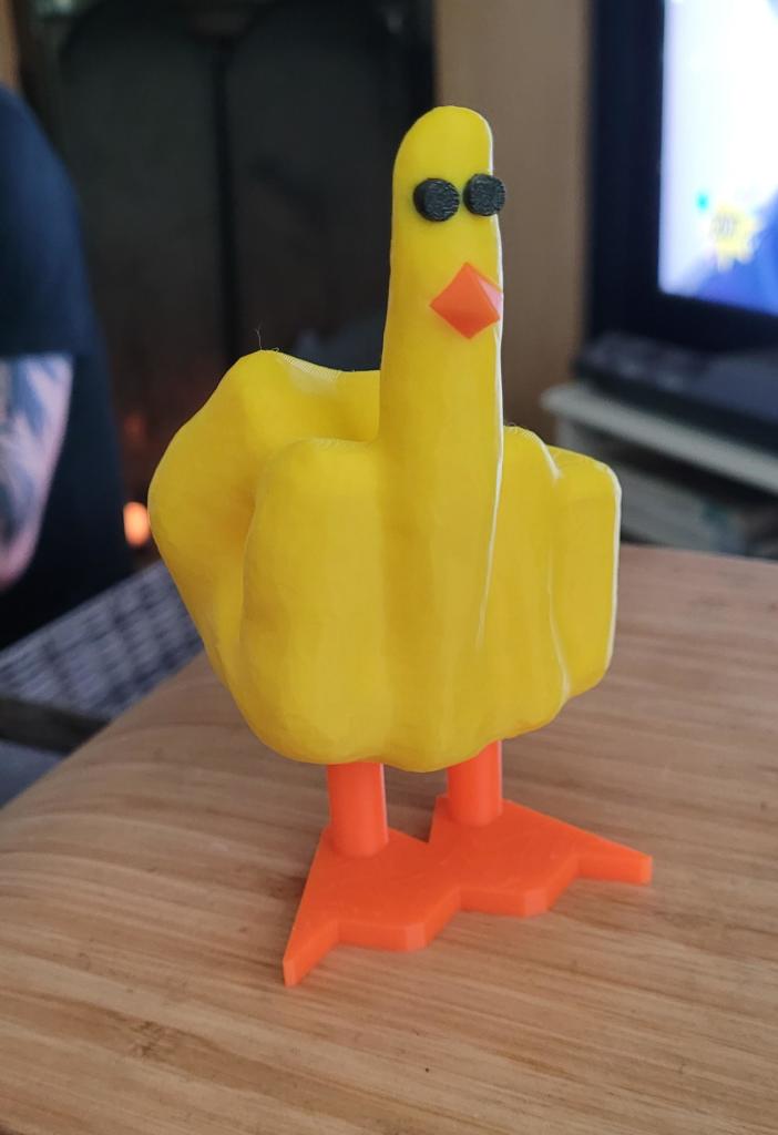 A photo of a very weird ornament - a bright yellow duck with orange feet, formed from a hand flipping the bird. 