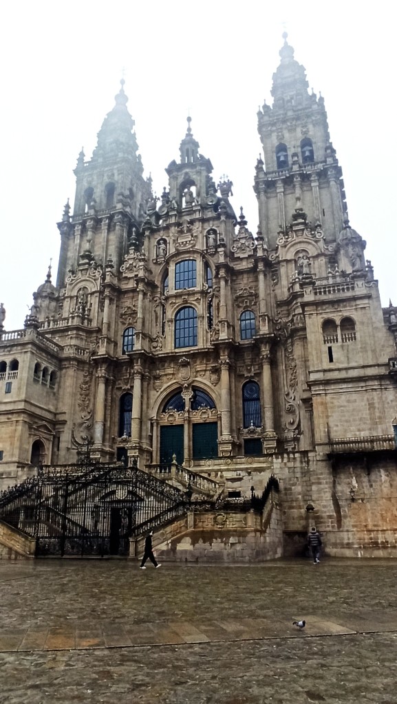 Un primer plano de la catedral de Santiago De Compostela desde la praza de abastos. Se ve gran parte del suelo mojado y cierta niebla arriba. Estaba poallando