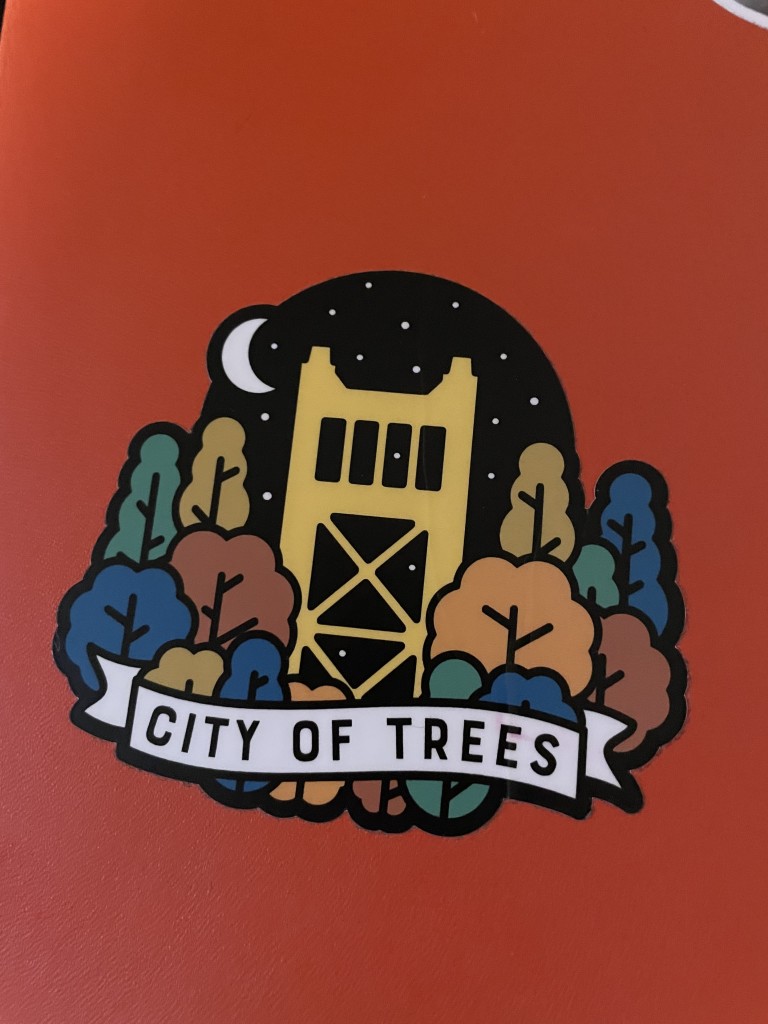 A sticker with the yellow Tower Bridge in Sacramento, surrounded by colorful trees, and a starry sky 