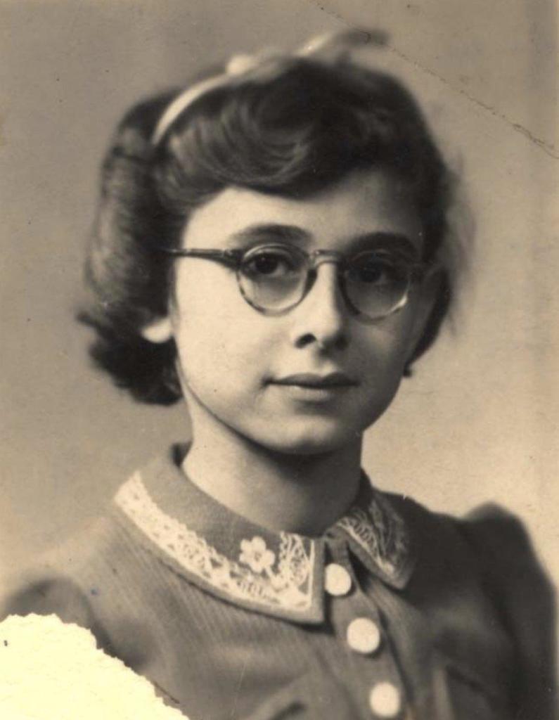 Vintage black-and-white portrait of a girl wearing round glasses and a collared dress with decorative details.