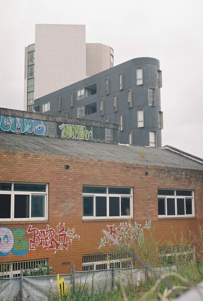 A warehouse in the foreground, with several apartment buildings of various modern styles in the background.