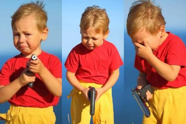 Toddler crying holding a gun.