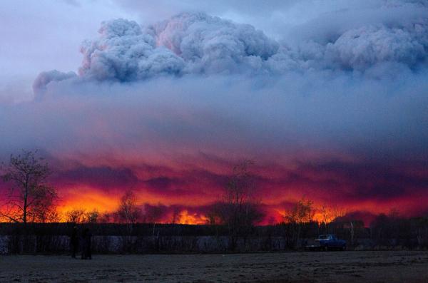 Boreal forest burning as smoke and ash rise to the sky.