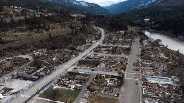 A town burned to the ground by a wildfire. Nothing remains except twisted metal and cement foundations.