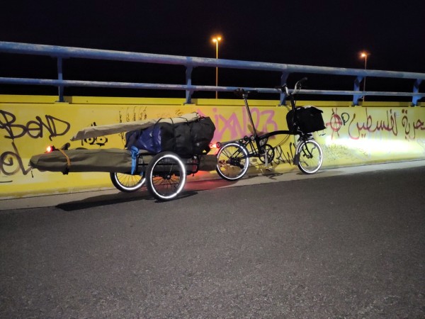 a brompton folding bicycle towing a trailer carrying a folding kayak