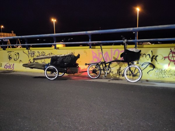 a brompton folding bicycle towing a trailer carrying a folding kayak