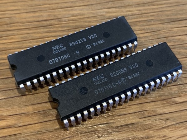 Two DIP packaged CPUs. One is labeled NEC V20, 42nd week of 1989. the other is a NEC V30 from 6th week 1992. 