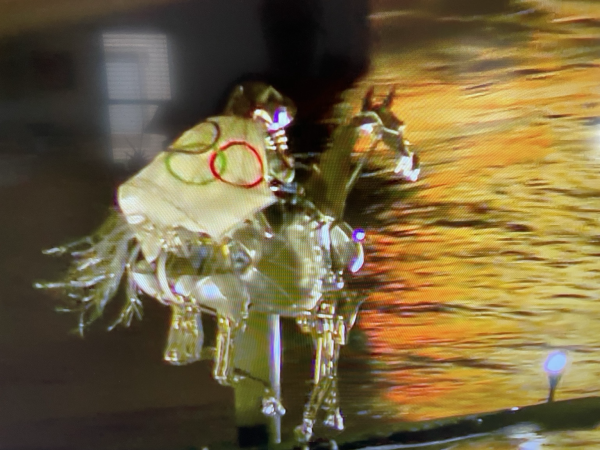 A mechanized horse and rider wrapped in the five ring Olympic flag races up the Seine 