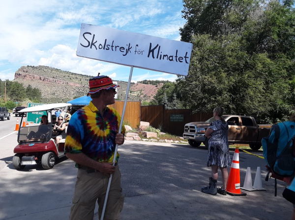 Image of me at entrance to festival grounds with a golf cart and a cliff in the background