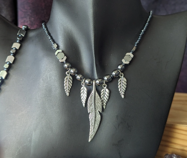 unisex necklace of hematite styled beads and 4 metallic silver feather pendants, 4 small ones and a large one in the middle/
and a silver arrows beaded bracelet