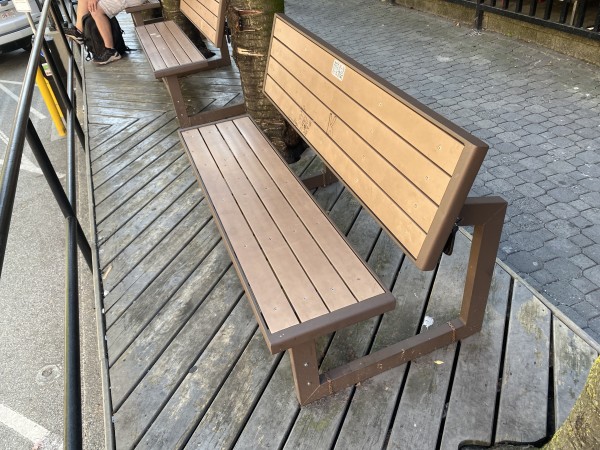 A bench that is convertible into a table, mounted next to an urban sidewalk