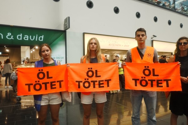 Drei Menschen halten Banner auf denen steht "Öl tötet"