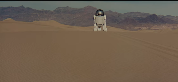 Small droid lost in the desert, with black mountains in distance. He's making strange squeaking noises and beeps and boops, and is looking for Obi Wan.