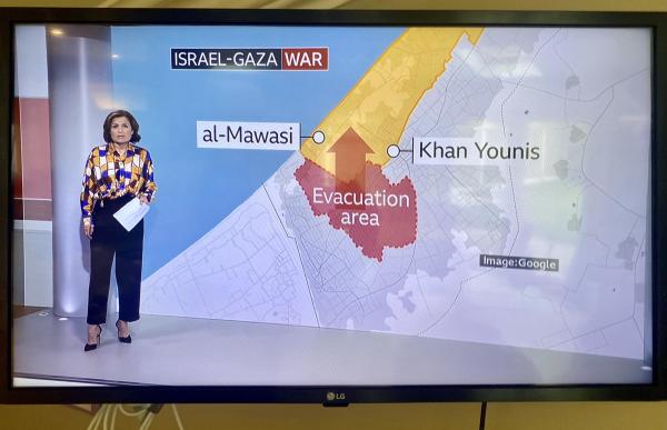 News presenter in front of a map labeled "Israel-Gaza War" highlighting an evacuation area between al-Mawasi and Khan Younis.