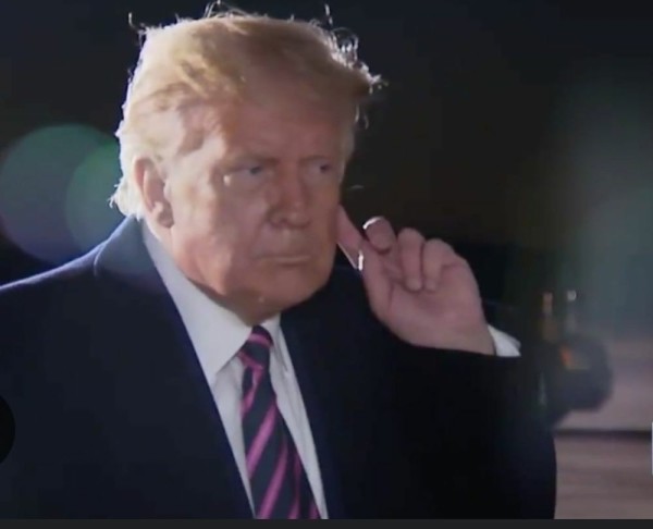 Trump holding up a finger to his ear in a listening posture