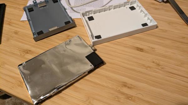 A Seagate USB hard disk in pieces on a bench. The hard disk is coated in a layer of plastic backed aluminium foil.