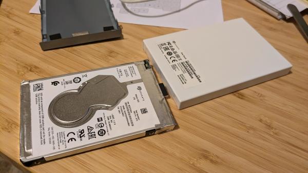 A Seagate USB hard disk in pieces on a bench. The top of the hard disk and the product label are visible.