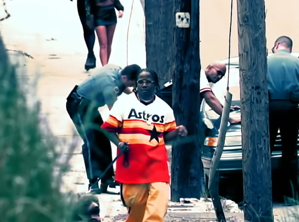 Big Boi walking a dog while wearing an Astros jersey