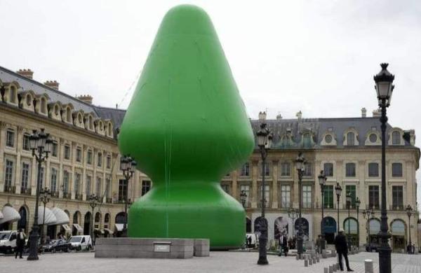 A huge modern cone shaped represention of a Xmas tree, in green, on a tapered base, in a European town square, and closely representing an enormous butt plug