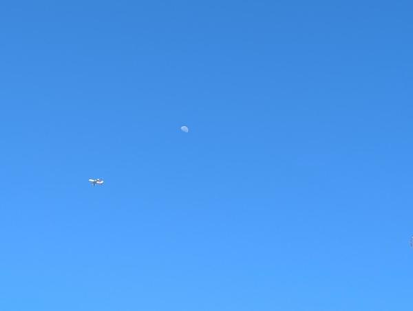 Blue sky, with a little aircraft and a bit of the moon