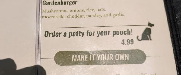 A cropped photo of a restaurant menu, showing an icon of a dog and the item "Order a patty for your pooch, $4.99"