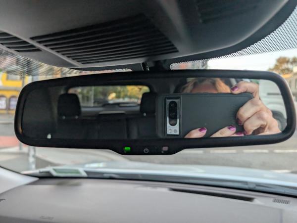 A revision mirror with part of my head, my phone and my fingers, below the mirror part is a green light power switch and a sensor