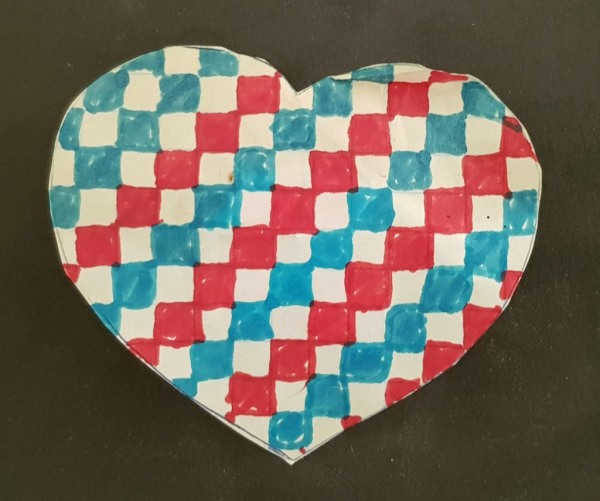 Hand-drawn and cut out heart on black card. The heart has a pattern of red and blue checks on white paper.