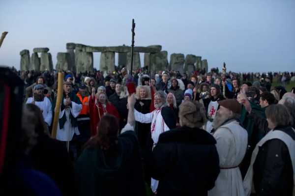 Druid leader Arthur Uther Pendragon, center, holds up his staff as he takes part in a Winter Solstice ceremony by the ancient stone circle of Stonehenge, in southern England, Dec. 21, 2012. (AP Photo/Matt Dunham, File)