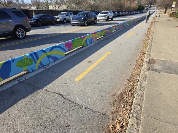 Blue, purple, and green concrete barriers along a 2-way cycle track