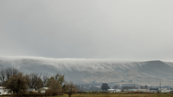 A ridge with low clouds near the top falling down the slope and evaporating about 1/3 of the way down.