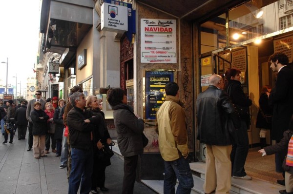 Viele Menschen stehen vor einem Lottobüro in Spanien an.