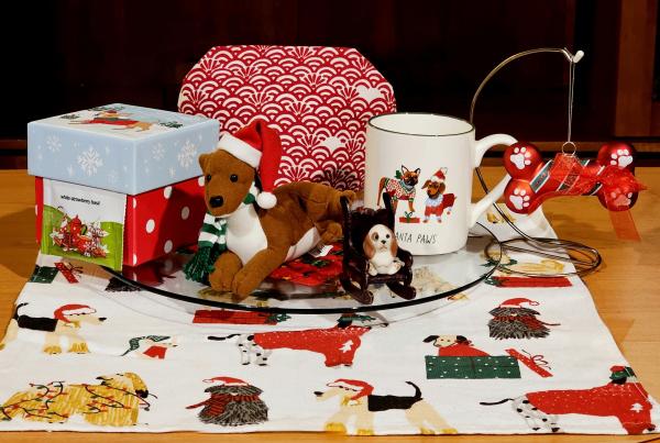 A tea tableau in white and red with dog-themed china & fabric, and a dog plushie  and dog ornaments. The tea is White Strawberry Basil white tea from Adagio.