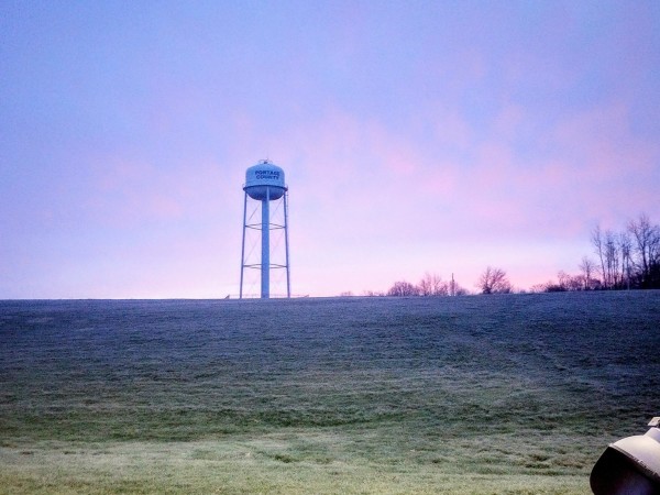 picture of water tower at the top of a grassy Hill