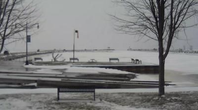 View looking northeast of the Oconto boat ramp and windsock in the foreground, with the breakwaters stretching into Sturgeon Bay behind it. // Image captured at: 2024-12-23 17:57:46 UTC (about 5 min. prior to this post) // Current Temp in Oconto: 32.09 F | .05 C // Precip: light snow // Wind: N at 0 mph | 0 kph // Humidity: 93%