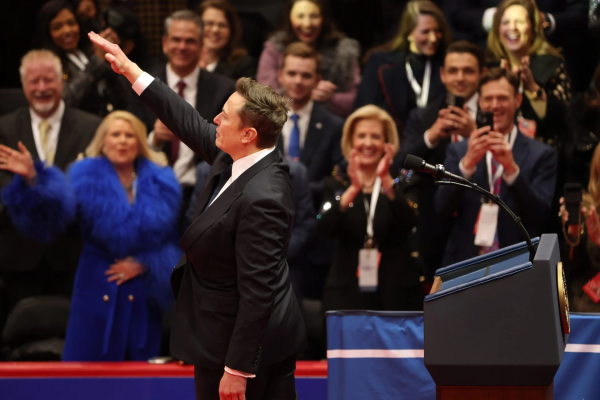 Elon Musk raises \his right arm Hitler-style in Nazi salute while an Inaugural crowd of smiling white people laugh and clap.